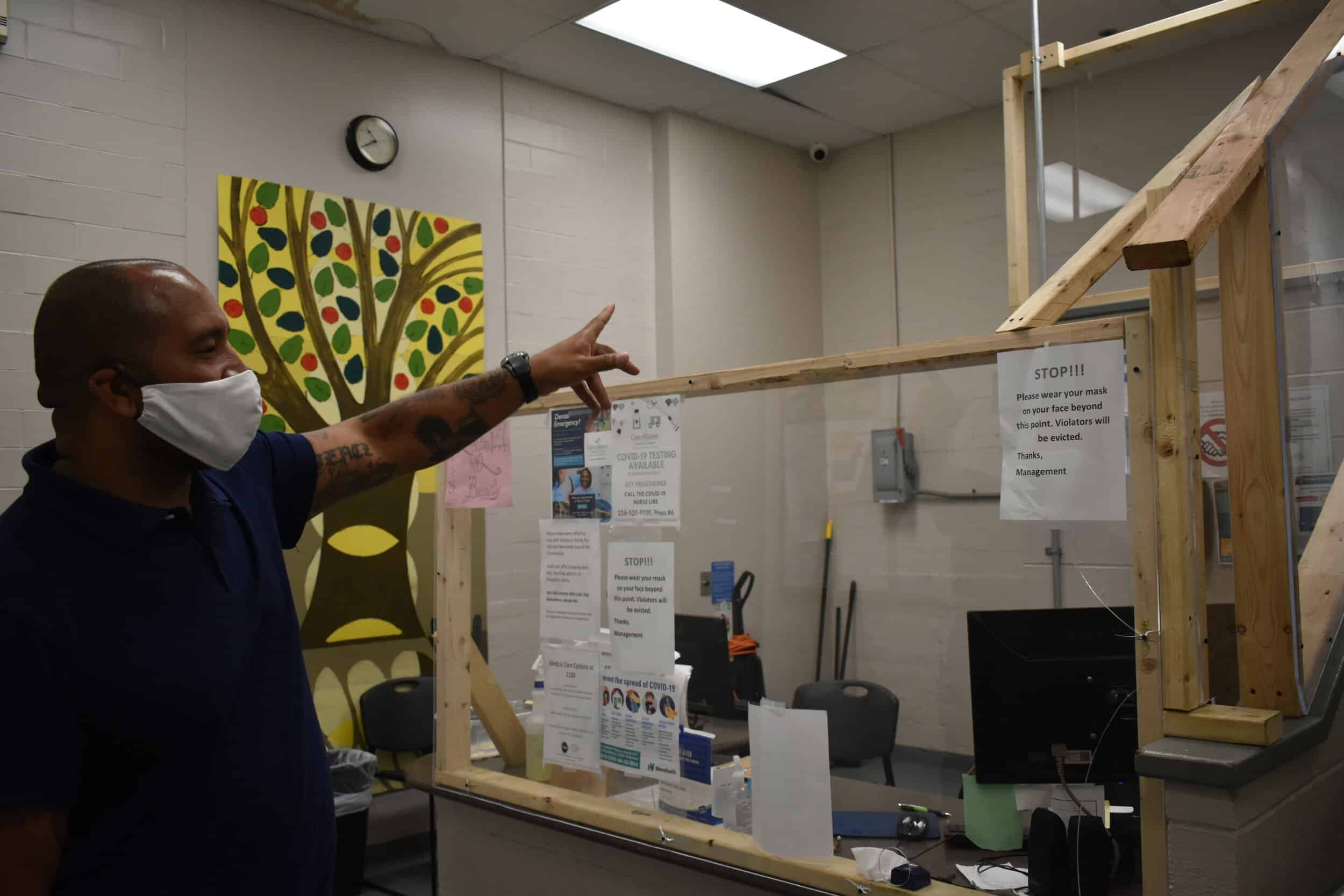 David Blunt, director of operations at Lutheran Metropolitan Ministry’s men’s shelter, shows how the shelter has set-up a plexiglass barrier at its entryway to protect residents and staff during the pandemic. Photo by Conor Morris.
