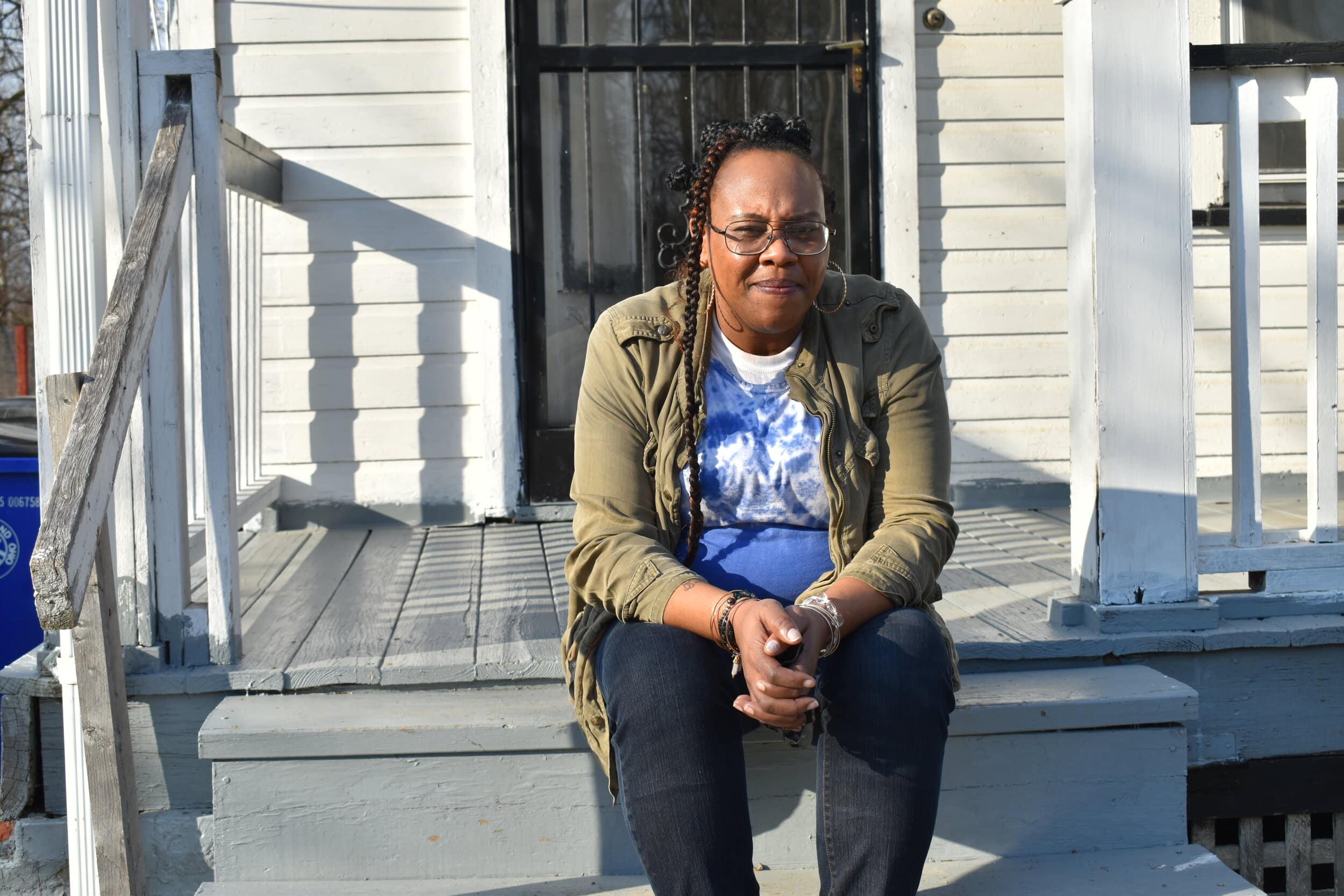 Denesha Moses sits on her porch in the Buckeye-Woodhill neighborhood. Moses received help from the Cleveland right to counsel program last year after her former landlord filed an eviction against her. Photos by Conor Morris.