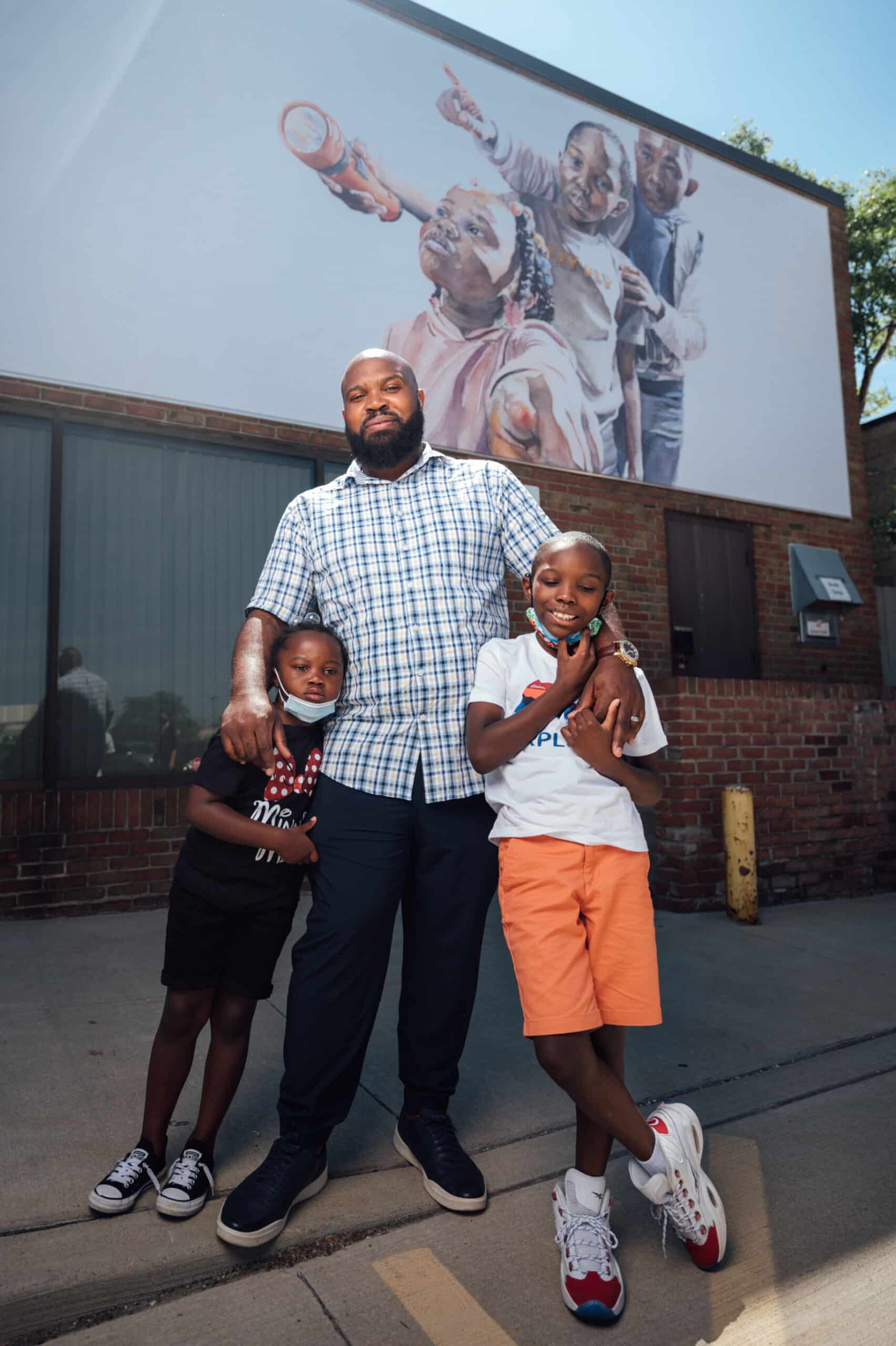 Darius Steward with his two children in front of the mural at the Lee-Harvard library branch.