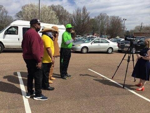 Rev. King, in green, speaks to the news media.