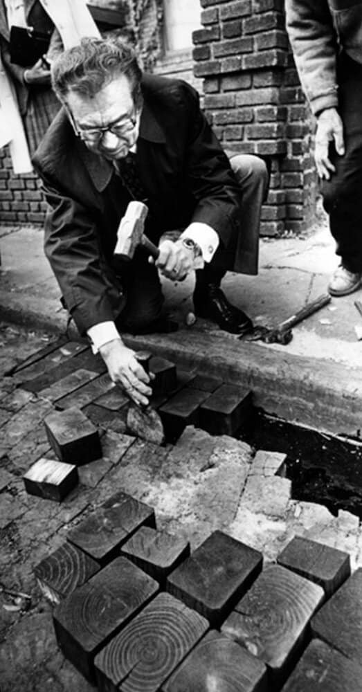 Mayor Ralph Perk helps repair Hessler Court’s wood block street in 1977.