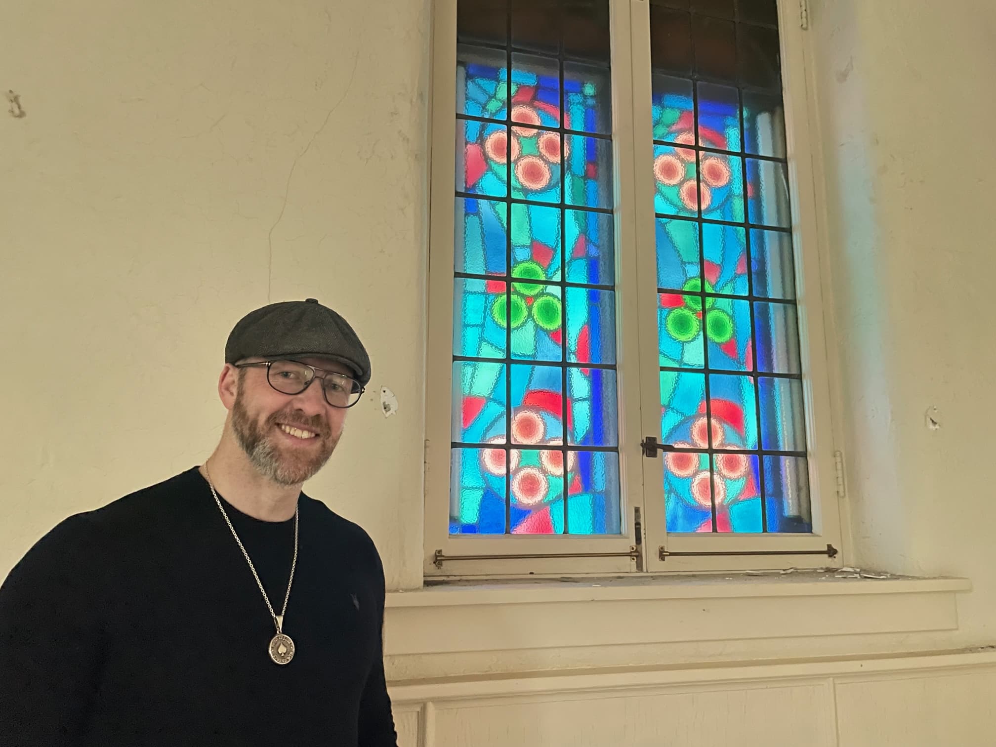 Zach Cooper in front of stained glass windows at 3929 Lorain Ave.