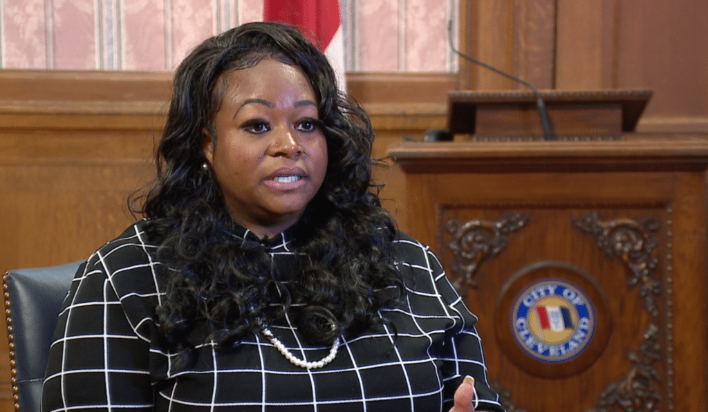 Leigh Anderson, a Black woman, sits in front of a podium.