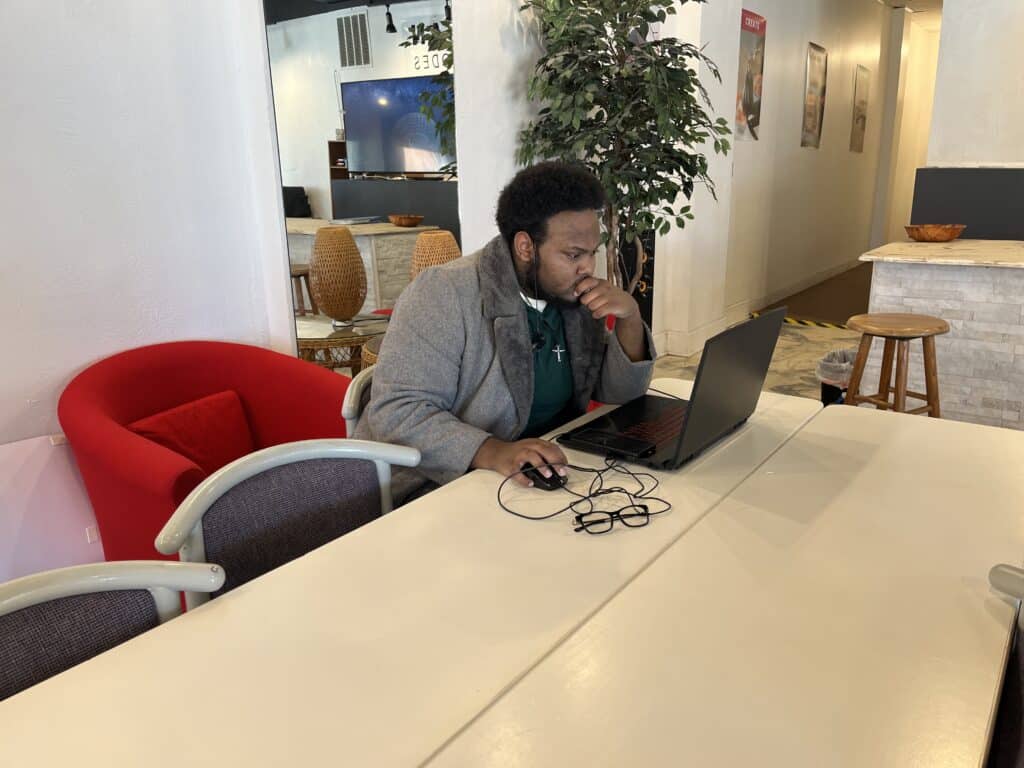 Mychael Gregg working on his computer at a table near the front desk at Urban City Codes. 

