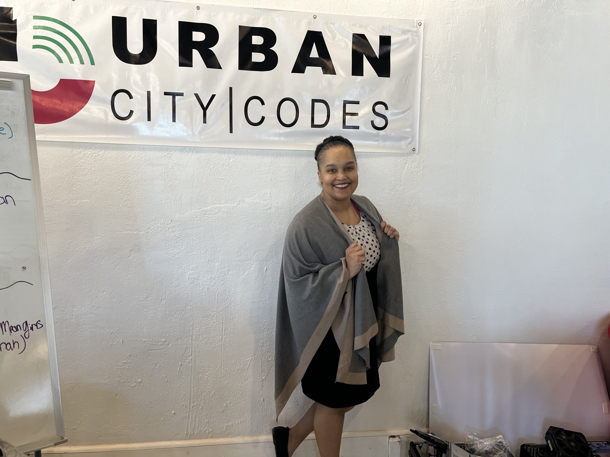 Tondi Allen standing next to a white board beneath a banner that reads “Urban City Codes.”
