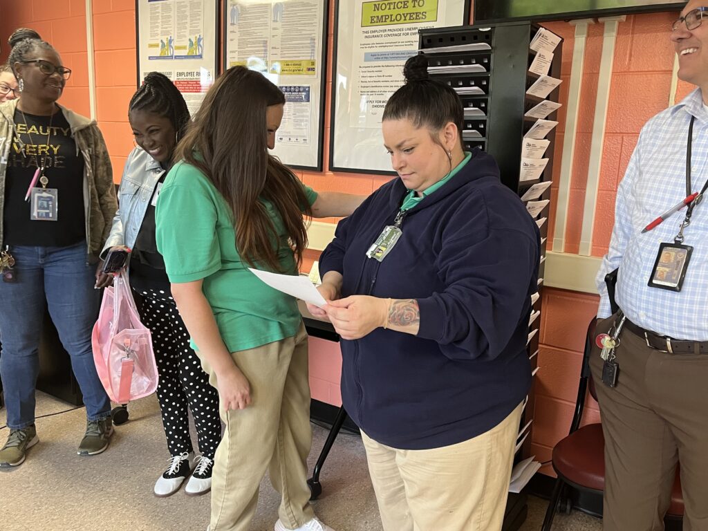Incarcerated people look at employment information and resources from a rack of papers with information about many Ohio counties. 