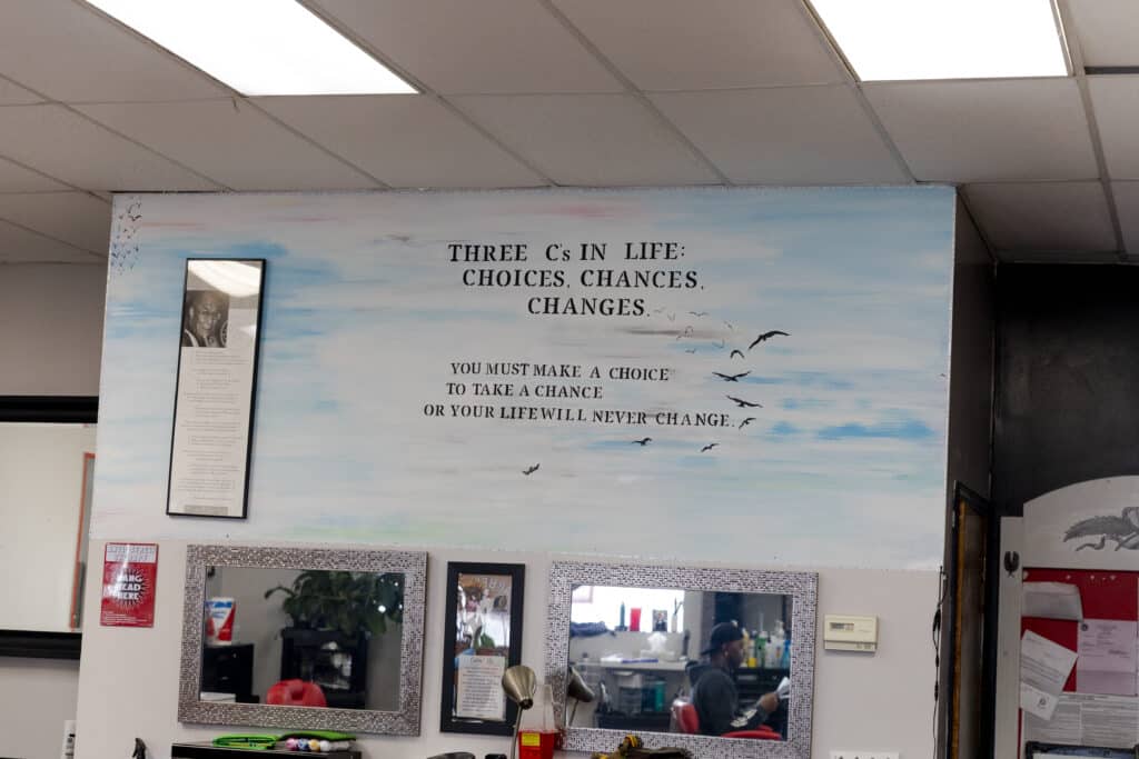 A mural inside a barbershop reads, “Three C’s in Life: Choices, chances, changes. You must make a choice to take a chance or your life will never change.”