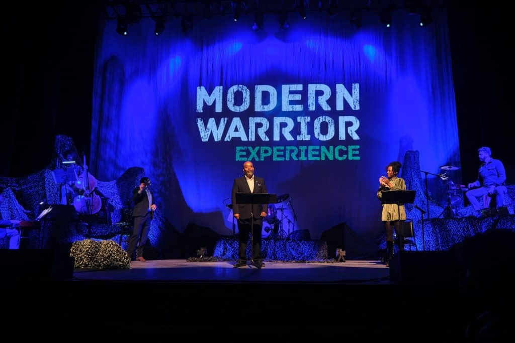 Gregory Reaves performing for Modern Warrior on June 17. A screen in the background reads, "MODERN WARRIOR EXPERIENCE."