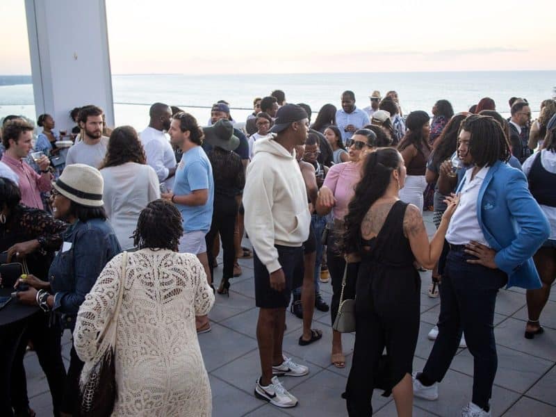 People gathered on a rooftop overlooking the water at a "For the Culture" mixer event.