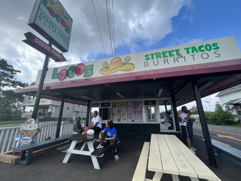 Customers sitting at picnic tables near the front window at Locos Street Tacos & Burritos.