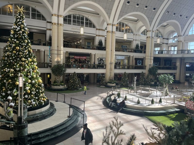 The Skylight Park in Tower City Center decorated for Christmas, including a large Christmas tree, pine boughs, and smaller Christmas trees.