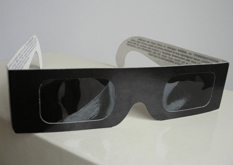Pair of cardboard eclipse shades on a white, neutral surface