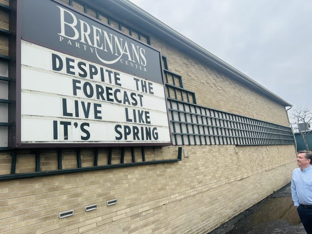 Jason Brennan stands next to the sign board his family-owned business is known for.