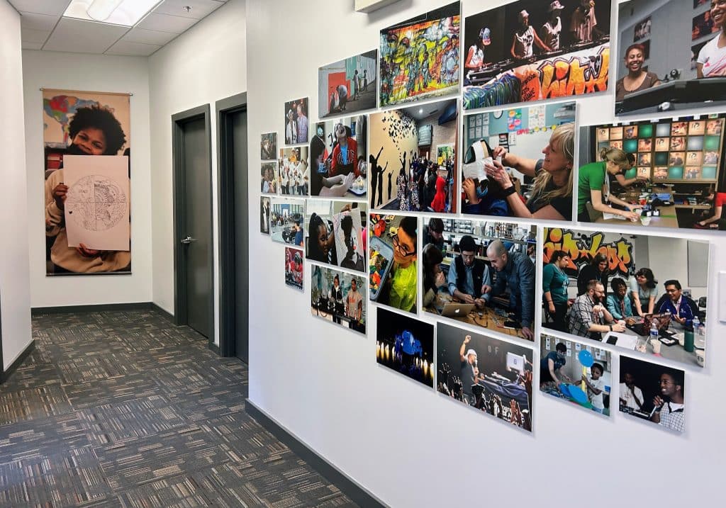 A photo of a hallway, covered in photographs from classrooms and art studios, showing students at work.