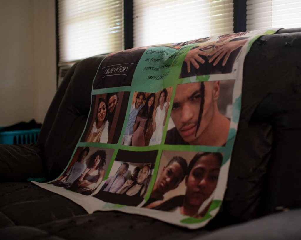 A photo of a green blanket with family photos and text is draped over the back of a couch. 