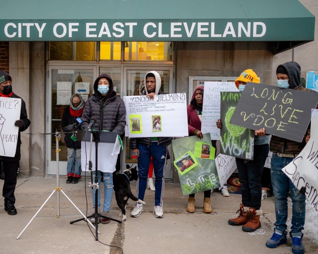 Left: A photo of people holding signs with photos and phrases like “Long Live VDOE” in front of a podium.   
