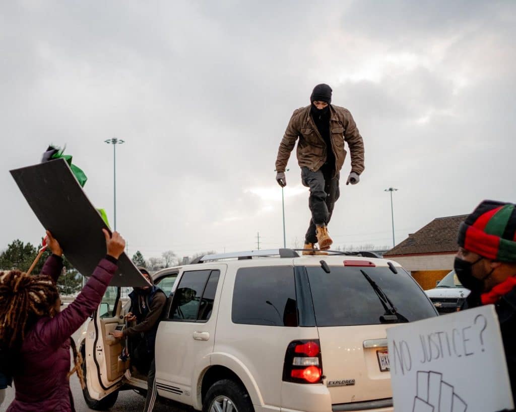 Right: A photo of a masked person standing on top of a white van during a protest.