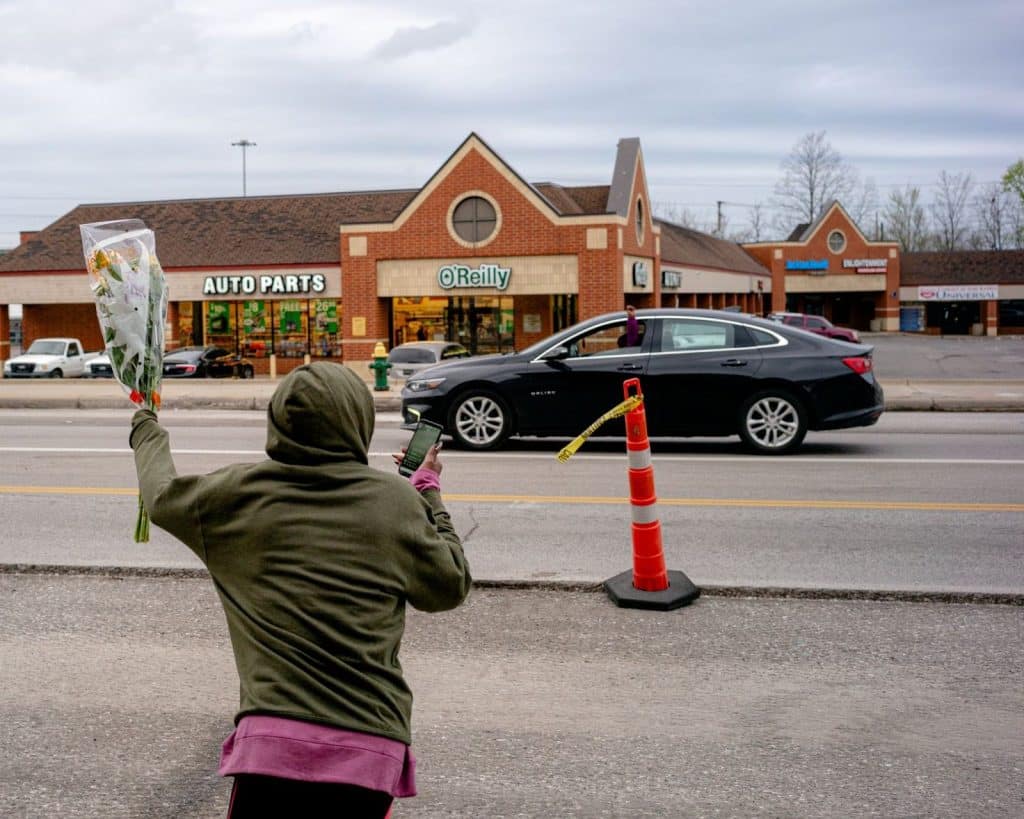 Left: A photo of a woman in a green hoodie holding up flowers toward a passing car.