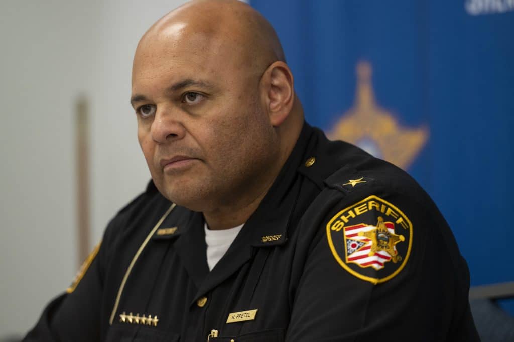 Cuyahoga County Sheriff Harold Pretel, a bald man with medium-toned skin, wears a black uniform with a sheriff’s patch on his left shoulder.